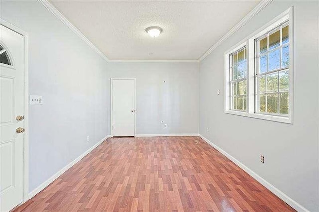 unfurnished room with baseboards, a textured ceiling, crown molding, and light wood finished floors