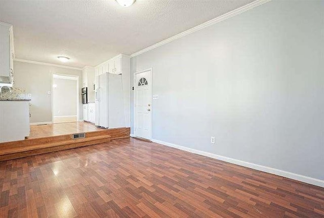 unfurnished room with a textured ceiling, baseboards, crown molding, and light wood-style floors