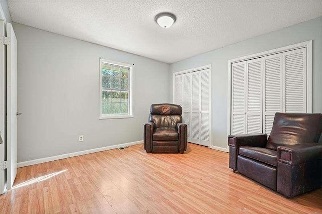 sitting room with baseboards, a textured ceiling, and light wood finished floors