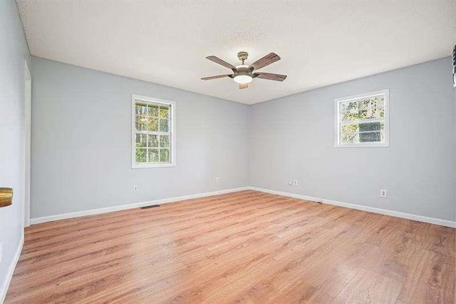 spare room featuring baseboards, light wood-style floors, visible vents, and ceiling fan