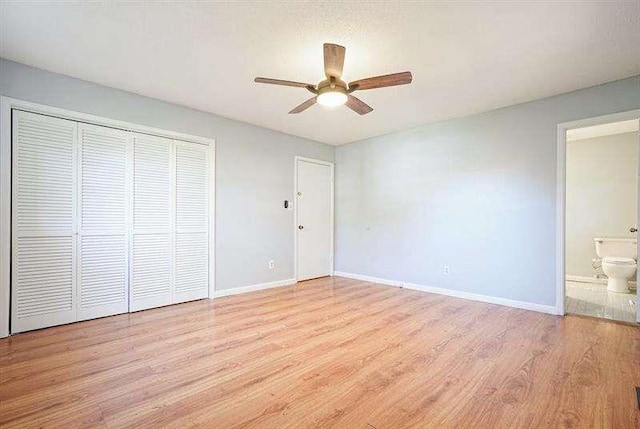 unfurnished bedroom with light wood-type flooring, baseboards, a closet, and ensuite bath