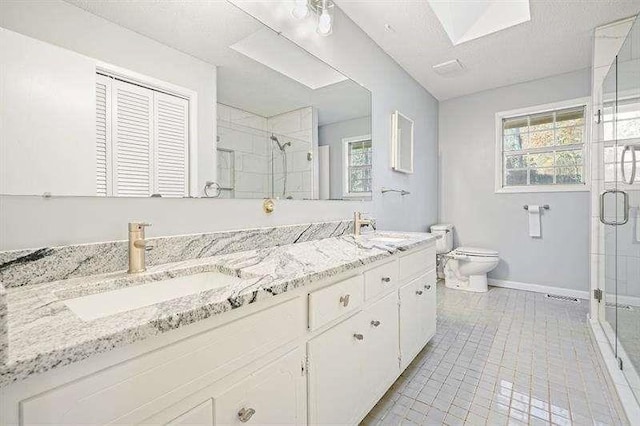 bathroom featuring a sink, toilet, a shower stall, and double vanity