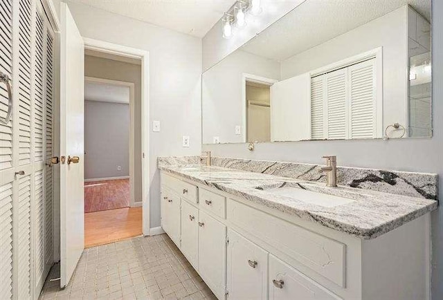 full bath with double vanity, baseboards, and a sink