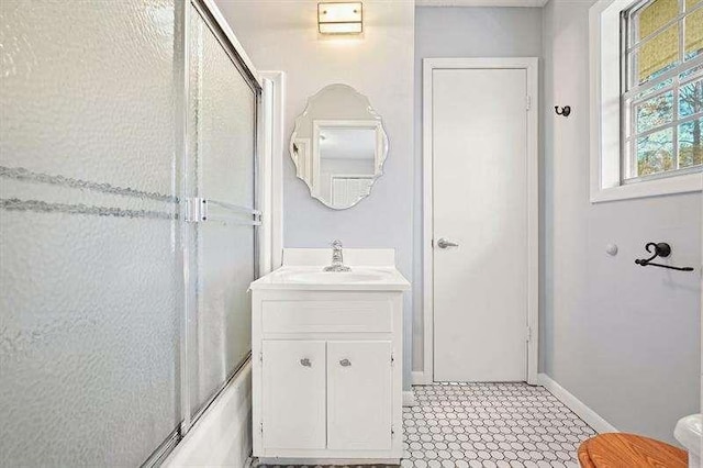 bathroom featuring baseboards, shower / bath combination with glass door, and vanity