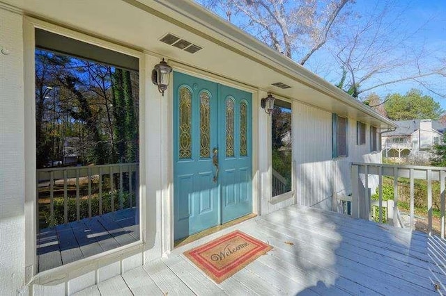 view of exterior entry featuring visible vents and a deck