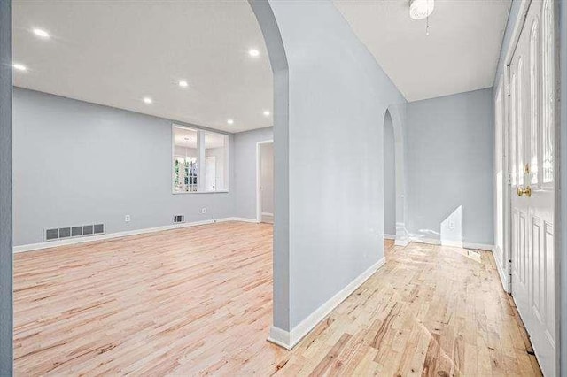 interior space with visible vents, baseboards, recessed lighting, wood finished floors, and arched walkways