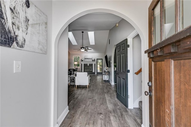 hallway with baseboards, vaulted ceiling, and wood finished floors