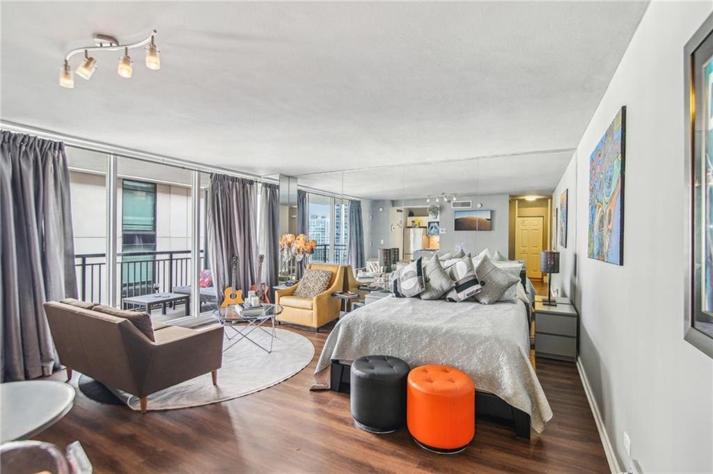 bedroom with access to exterior, hardwood / wood-style flooring, and a wall of windows