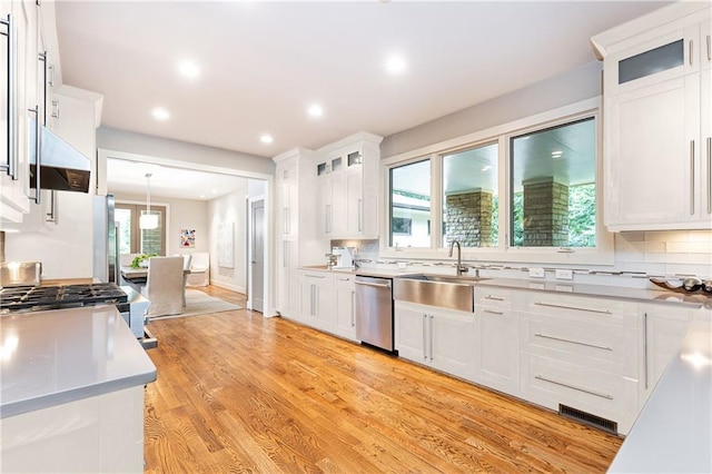 kitchen with light wood-type flooring, dishwasher, white cabinetry, and pendant lighting