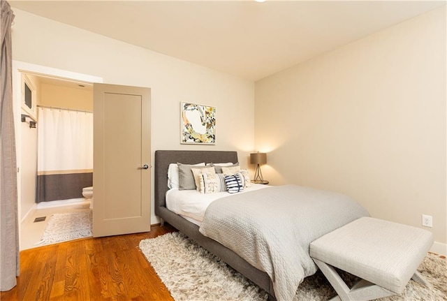 bedroom with ensuite bath and dark hardwood / wood-style flooring