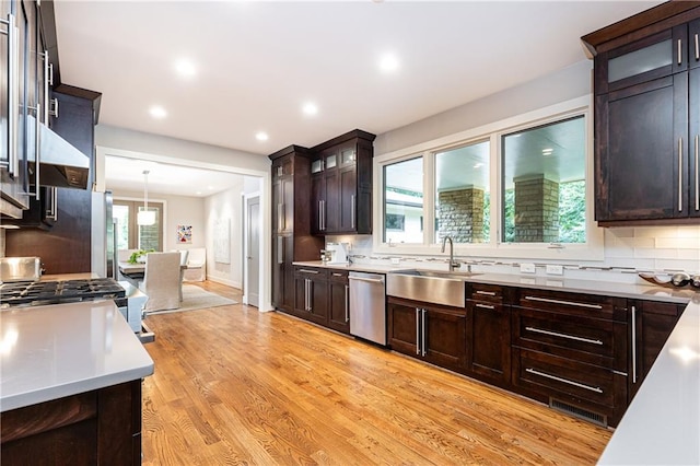 kitchen with decorative light fixtures, light hardwood / wood-style floors, tasteful backsplash, and a wealth of natural light