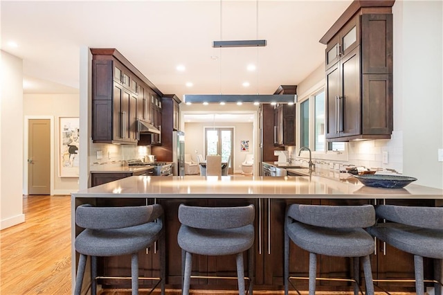 kitchen featuring sink, range, light hardwood / wood-style flooring, and tasteful backsplash