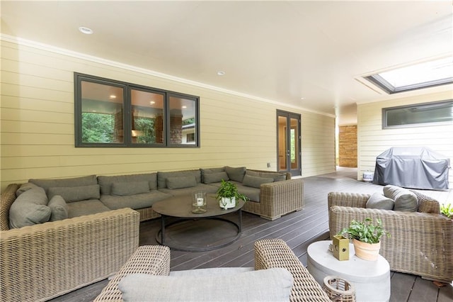 living room with crown molding, wooden walls, a skylight, and dark hardwood / wood-style flooring