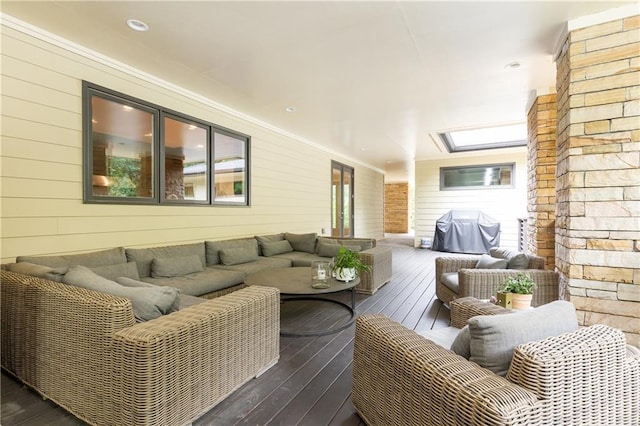 living room featuring wood walls, dark wood-type flooring, and a skylight