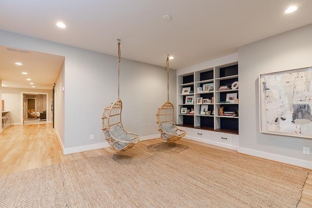 unfurnished room featuring built in features and hardwood / wood-style floors