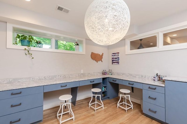 home office featuring light wood-type flooring and built in desk