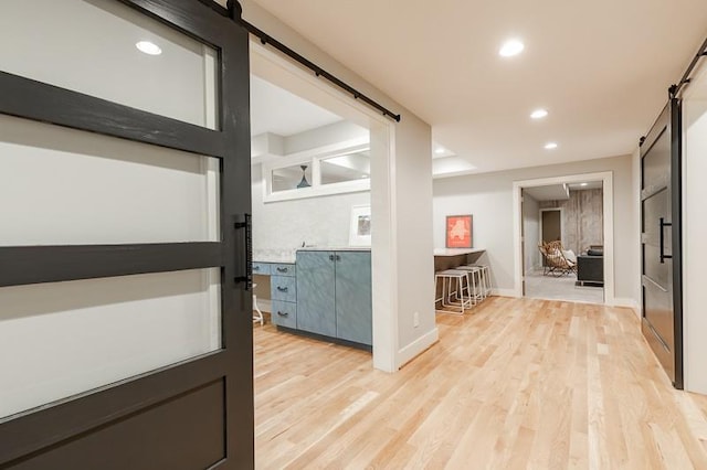 corridor with light wood-type flooring and a barn door