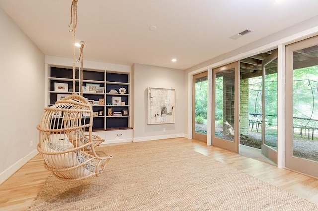 living area featuring built in shelves and hardwood / wood-style floors