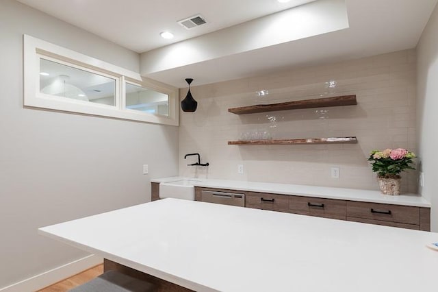 bar with sink, light hardwood / wood-style floors, decorative light fixtures, and dishwasher