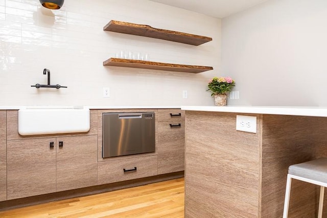 kitchen featuring sink, stainless steel dishwasher, and light hardwood / wood-style flooring