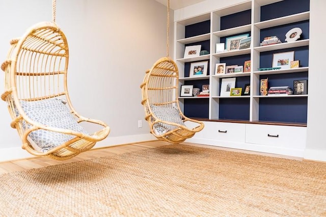 living area with built in shelves and hardwood / wood-style floors