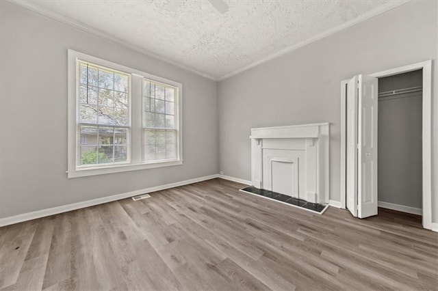 interior space featuring ornamental molding, light wood-type flooring, a textured ceiling, and a fireplace