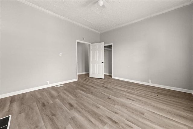 unfurnished bedroom with ceiling fan, hardwood / wood-style flooring, ornamental molding, and a textured ceiling