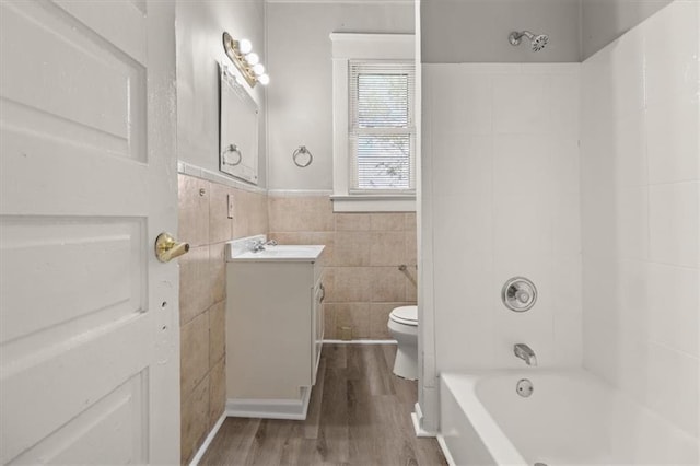 full bathroom with tile walls, shower / bath combination, vanity, wood-type flooring, and toilet