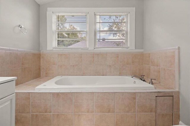 bathroom featuring a relaxing tiled tub and vanity