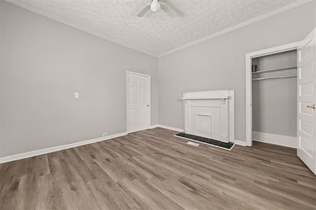 unfurnished bedroom featuring a closet, a textured ceiling, ceiling fan, hardwood / wood-style flooring, and ornamental molding