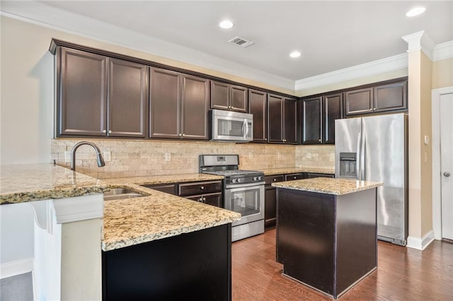 11686 Davenport Ln, Alpharetta, GA 30005 - kitchen featuring appliances with stainless steel finishes, a sink, light stone countertops, dark brown cabinetry, and ornamental molding