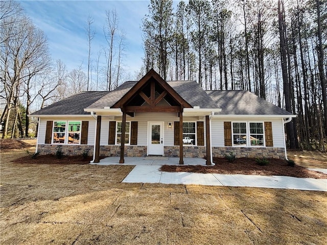 craftsman house with a porch, stone siding, and a shingled roof