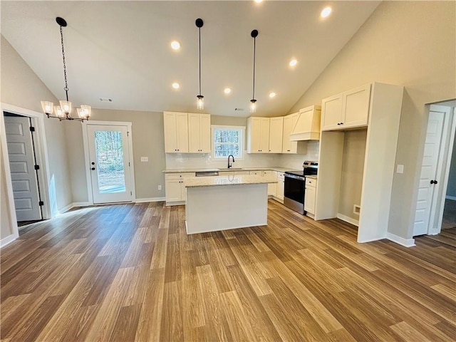 kitchen featuring a center island, premium range hood, stainless steel electric stove, wood finished floors, and white cabinetry