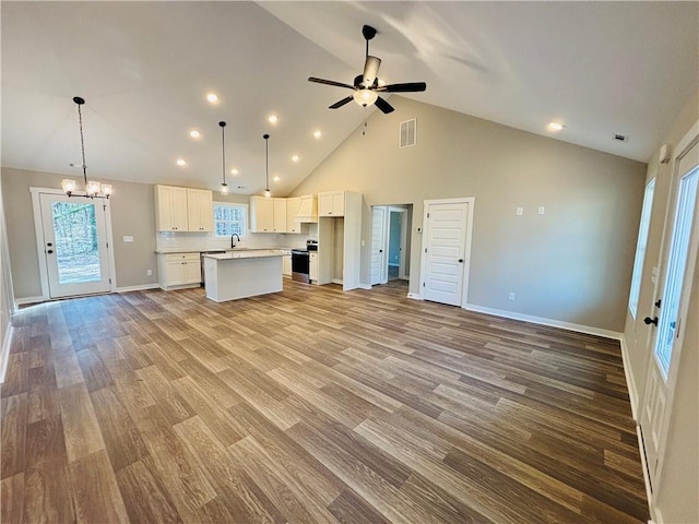 kitchen featuring visible vents, a kitchen island, open floor plan, stainless steel range with electric cooktop, and white cabinets