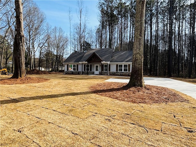 view of front of home featuring a porch, stone siding, and driveway