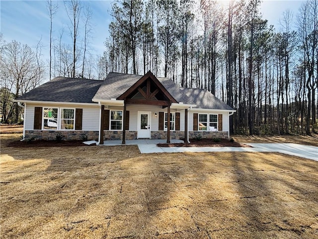 craftsman-style home with a porch, stone siding, and a shingled roof