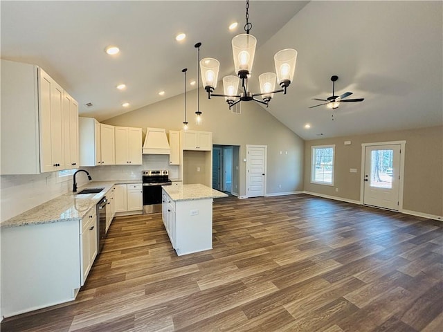 kitchen with custom range hood, a sink, light stone counters, white cabinetry, and stainless steel appliances