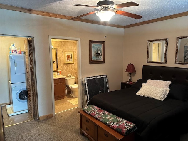 bedroom with stacked washing maching and dryer, ensuite bathroom, a textured ceiling, ceiling fan, and a closet