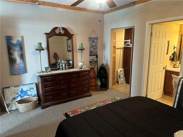 bedroom featuring light carpet, ensuite bathroom, a spacious closet, and ceiling fan