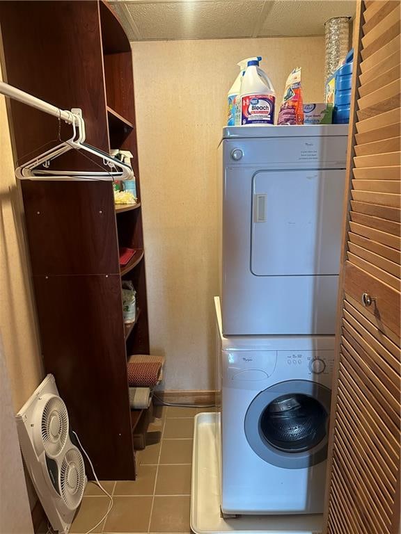 clothes washing area with light tile patterned floors and stacked washing maching and dryer