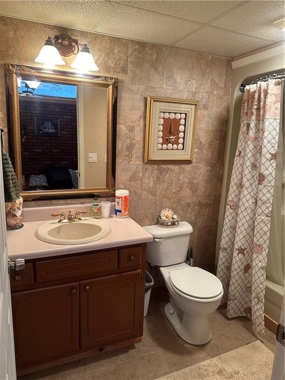 full bathroom with tile patterned floors, shower / tub combo, vanity, toilet, and a paneled ceiling