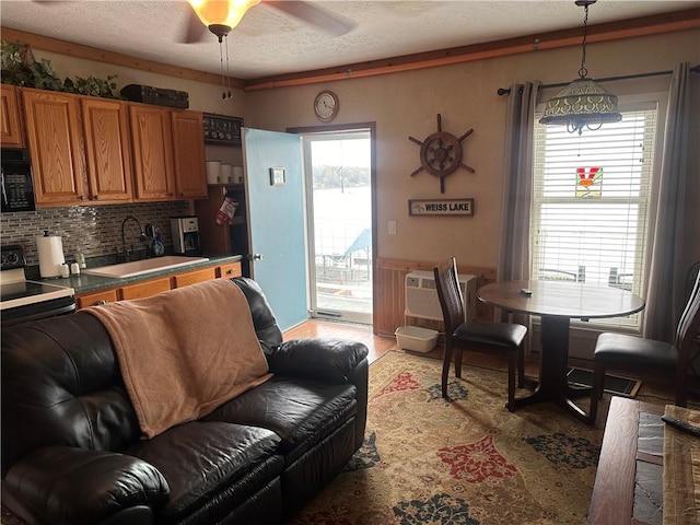 living room with a textured ceiling, a wall unit AC, ceiling fan, and sink