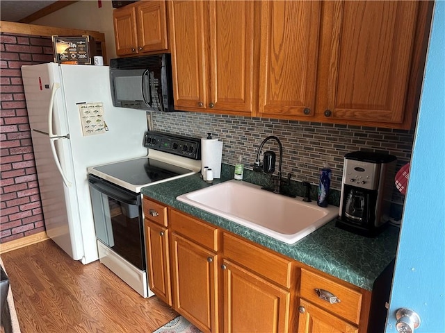 kitchen with white appliances, tasteful backsplash, light hardwood / wood-style flooring, and sink