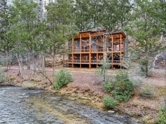 back of house with a water view and a view of trees