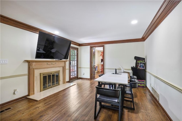 dining area featuring dark wood finished floors, ornamental molding, visible vents, and a fireplace