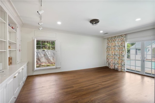 spare room with rail lighting, crown molding, baseboards, and dark wood-style floors