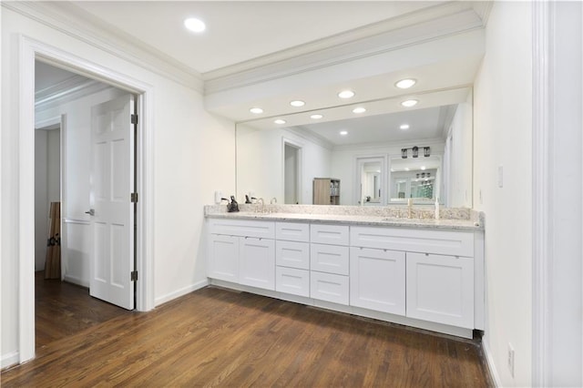 bathroom featuring wood finished floors, baseboards, ornamental molding, and a sink