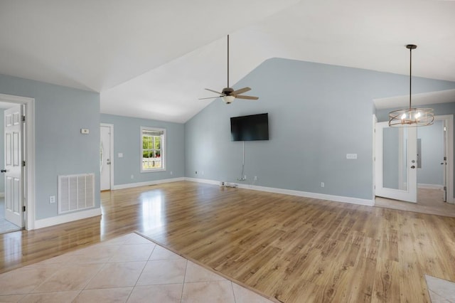 unfurnished living room with lofted ceiling, light tile patterned floors, visible vents, and ceiling fan with notable chandelier