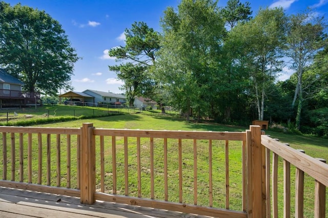 wooden terrace featuring a yard and fence