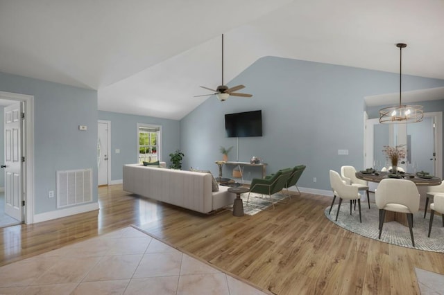 living room featuring light tile patterned floors, visible vents, vaulted ceiling, baseboards, and ceiling fan with notable chandelier